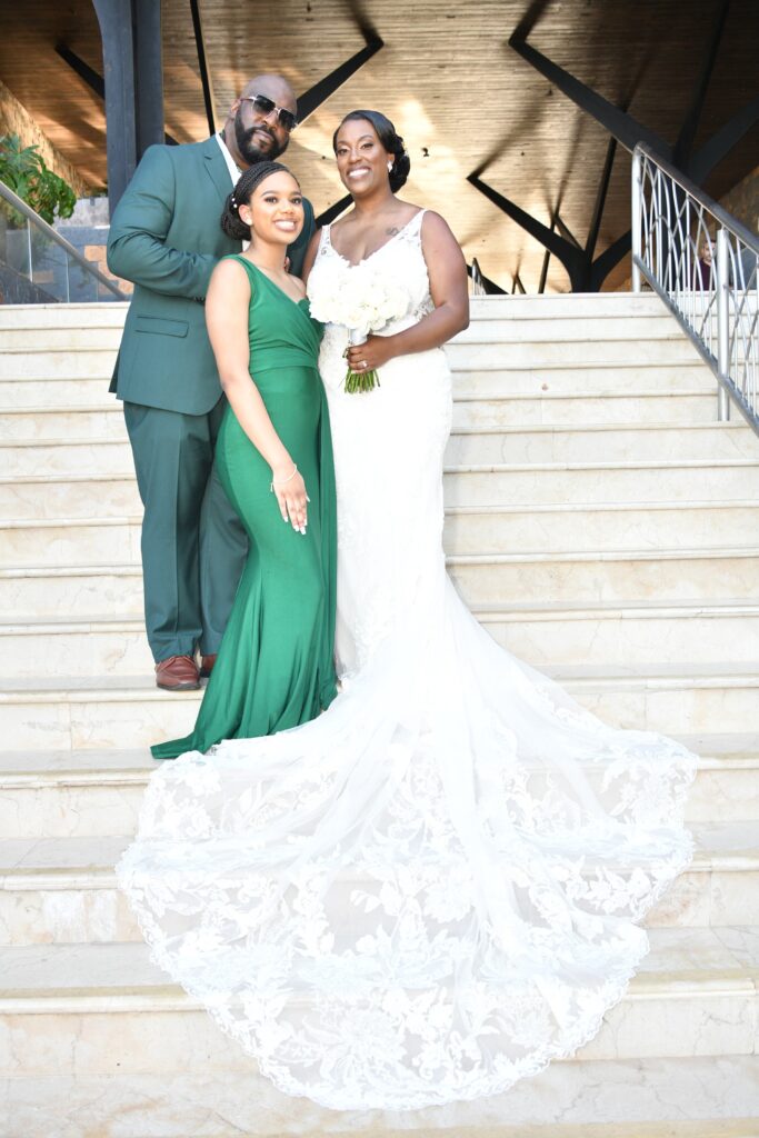 Maresha & Dywon and their daughter on the steps of Dreams Natura in Riviera Cancun, Mexico for their destination wedding