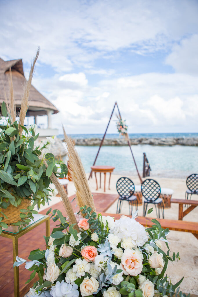 wedding ceremony set up on the beach with triangular ceremony centerpiece and florals