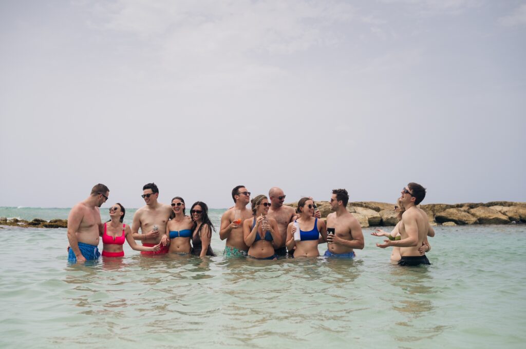 Wedding party celebrating in ocean water with drinks and tropical backdrop