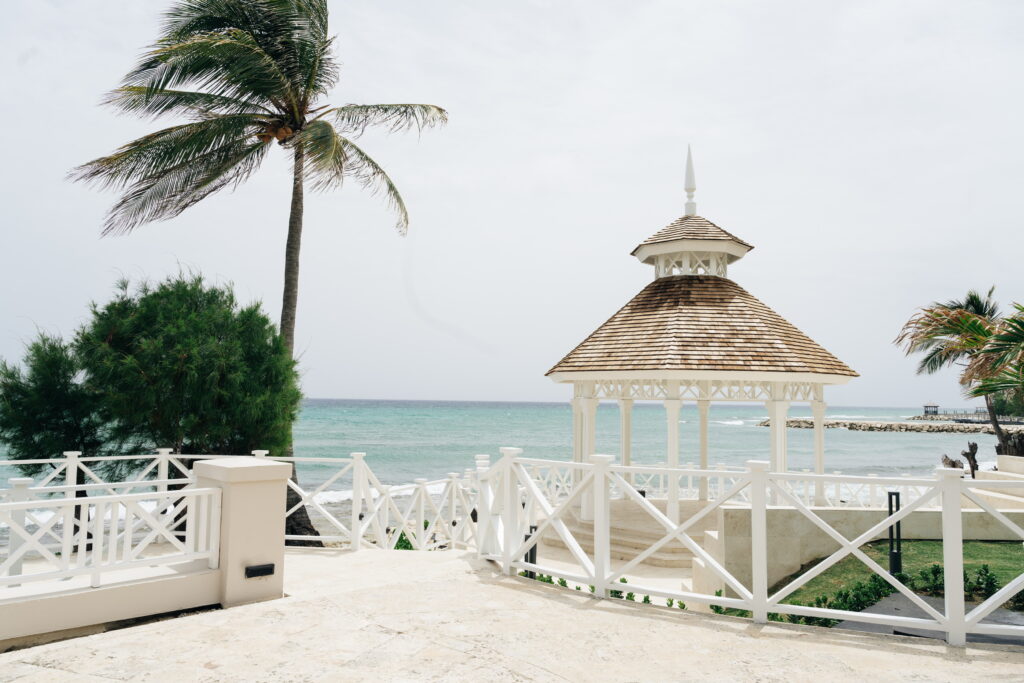 White wedding gazebo with tropical palm trees and turquoise ocean backdrop